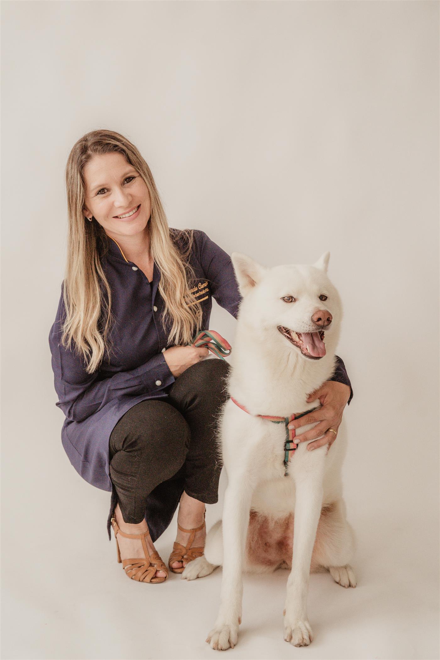 Dra. Amanda ao lado de um cão branco, em um momento de carinho